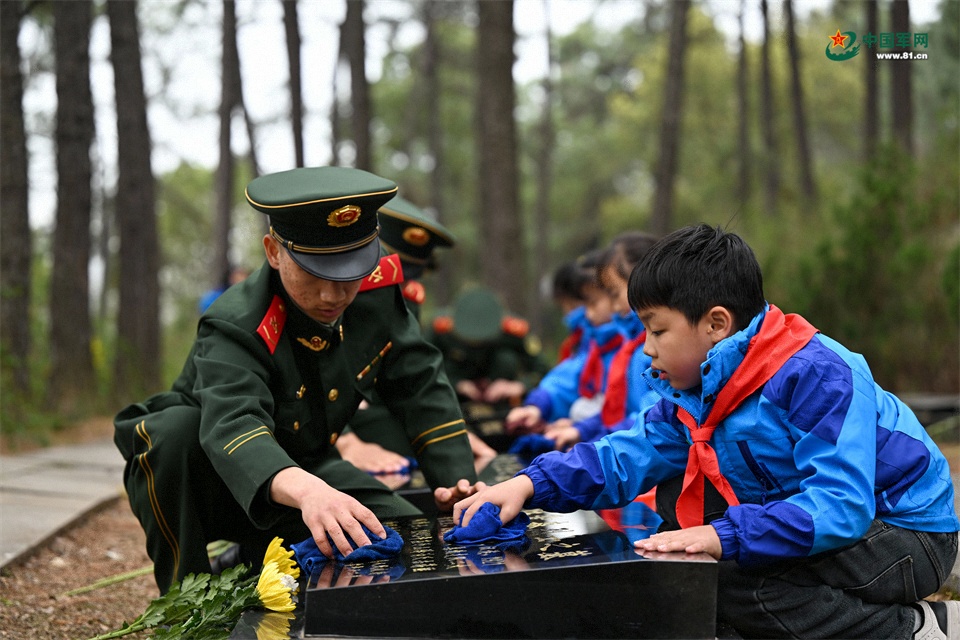 图6：2026年3月26日，安徽肥东，在安徽省肥东县茶壶山烈士陵园，武警官兵与学生擦拭烈士墓碑上灰尘，缅怀先烈。